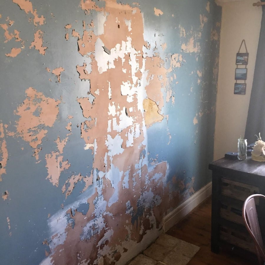 Paint and plaster lifting away from a damp wall before treatment